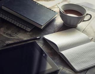 diary, notebooks, tablet and cup of coffee on the table